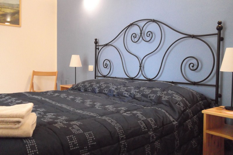 Camera Violetta con letto in ferro e toni delicati